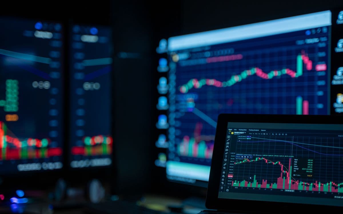 Monitors showing market charts in a dim room